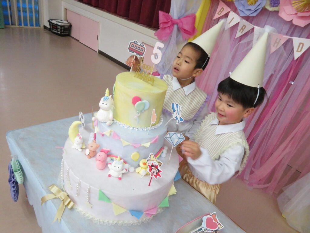 大きなケーキに飾り付けする子どもたち