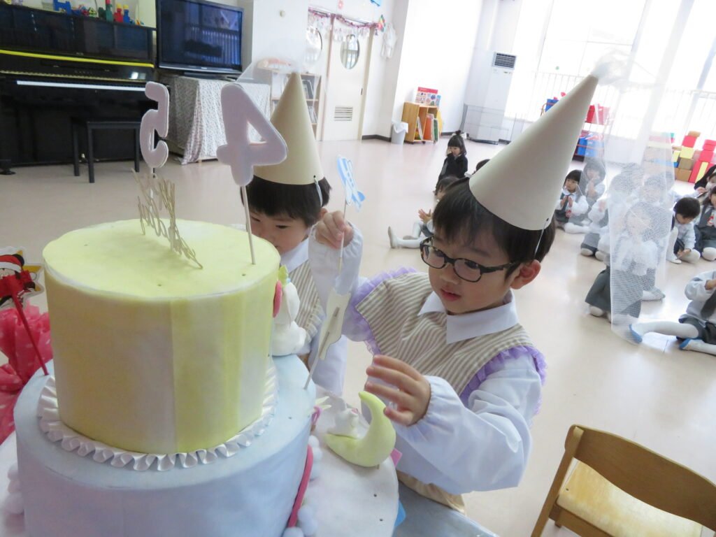 大きなケーキに飾り付けする子どもたち