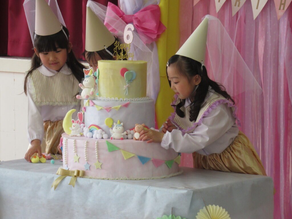 誕生日ケーキに飾り付けをする園児