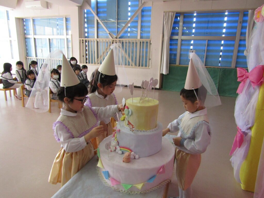 大きなケーキに飾り付けをする誕生児たち