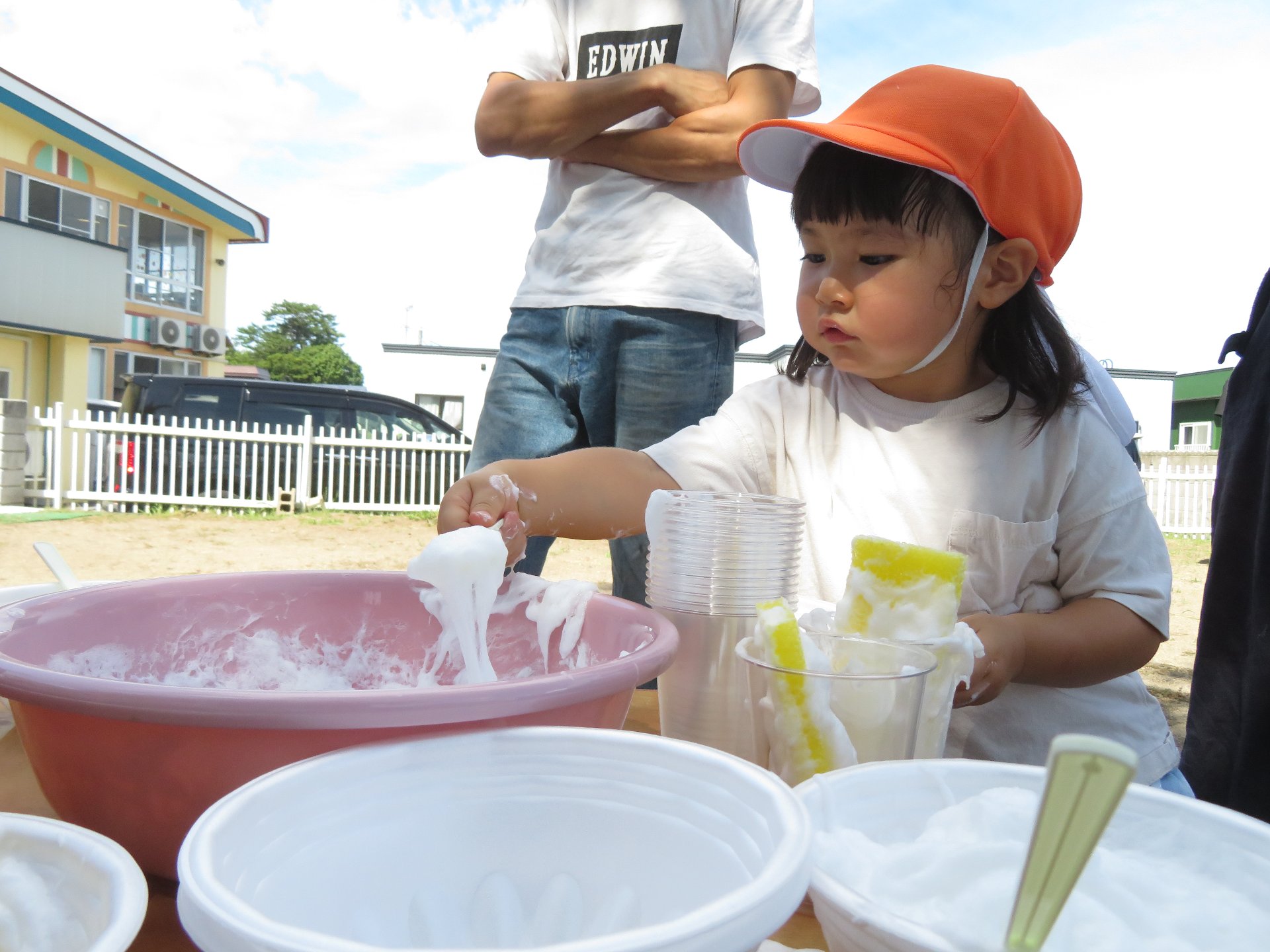 洗面器にスプーンで泡を入れる園児たち