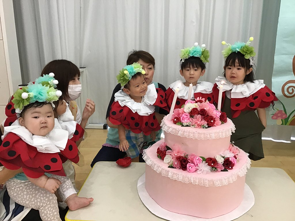 誕生日ケーキの火を消す誕生児たち