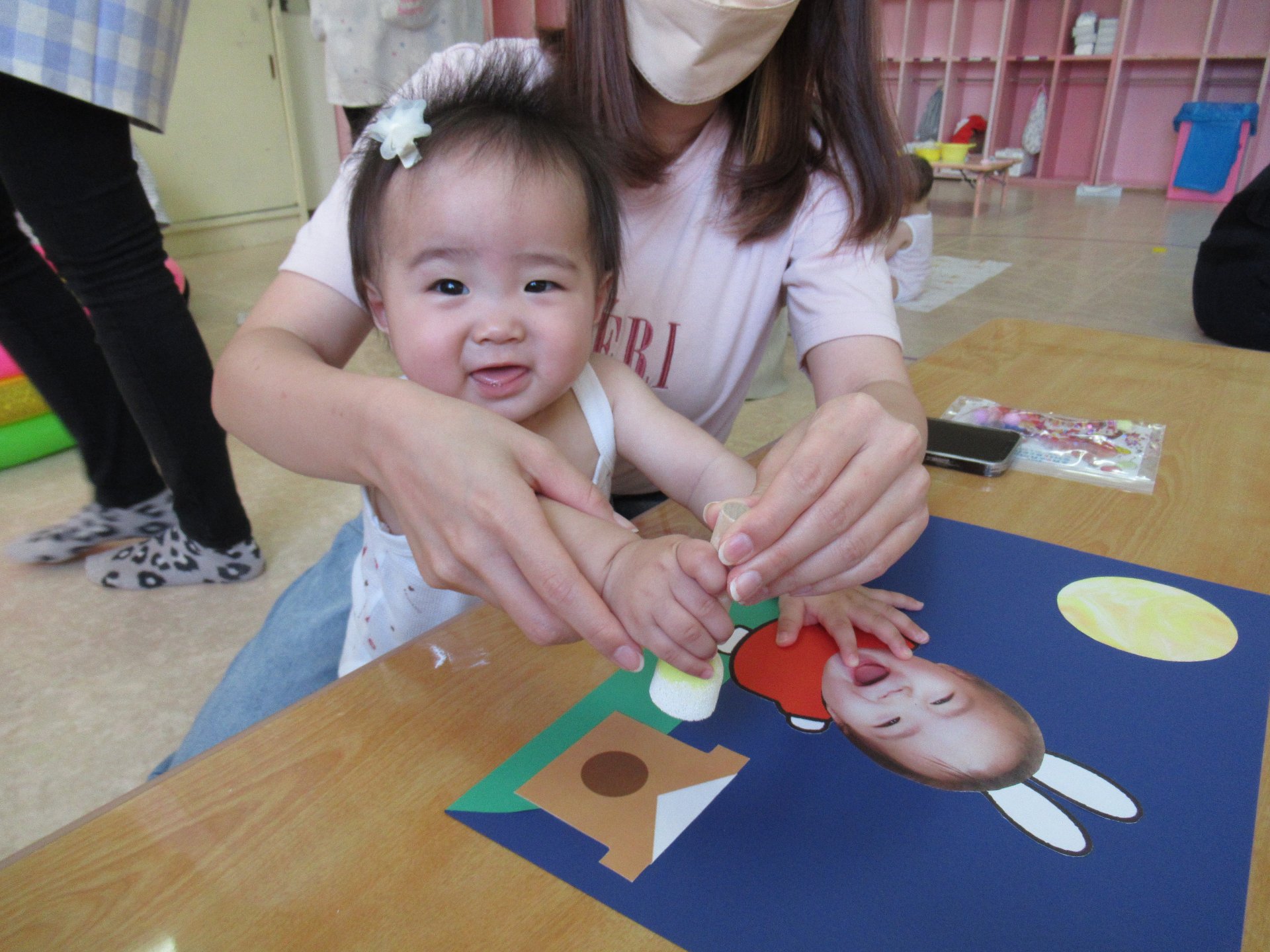 お父さんとお母さんとつづり制作のお団子をスタンプを押す園児