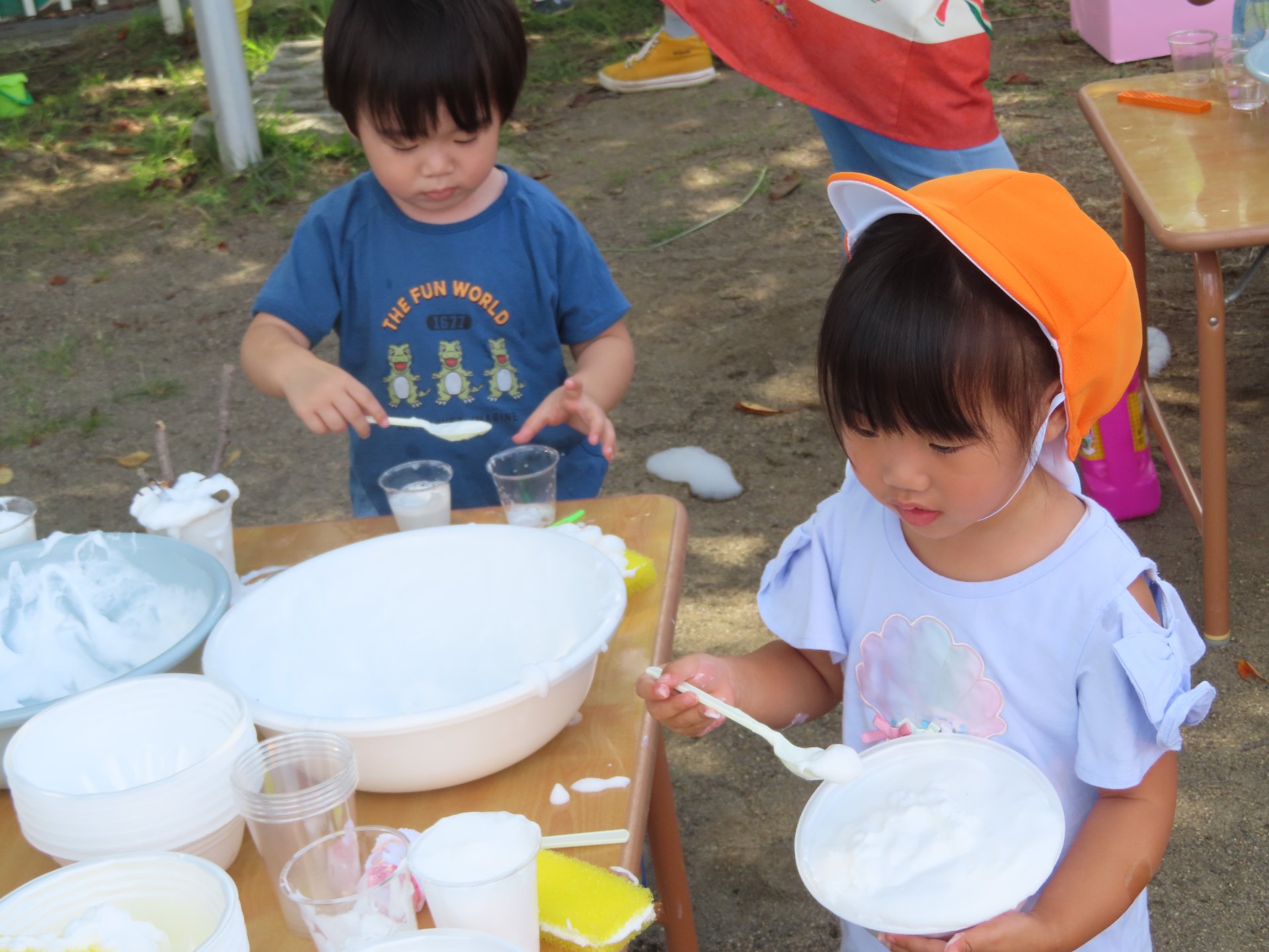 洗面器にスプーンで泡を入れる園児たち