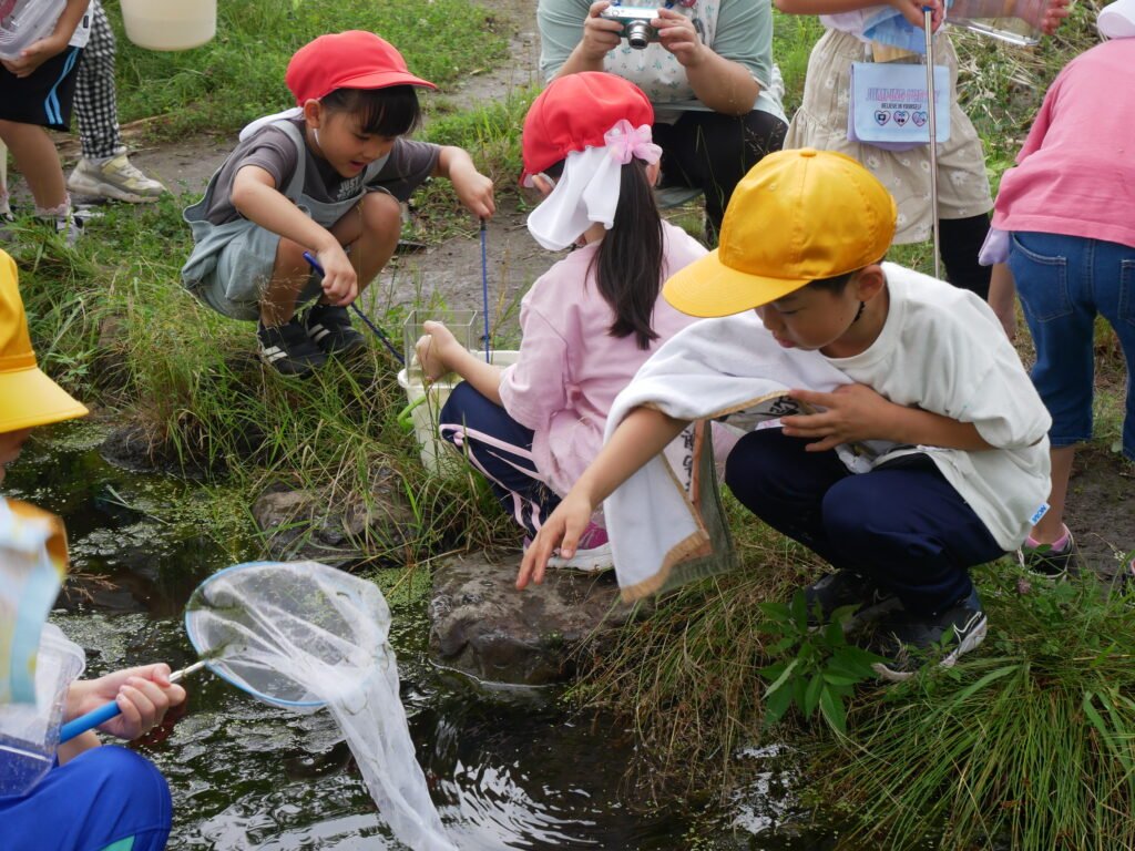 生き物を捕まえたり、草花を摘んだりして  活発に遊ぶ子どもたち