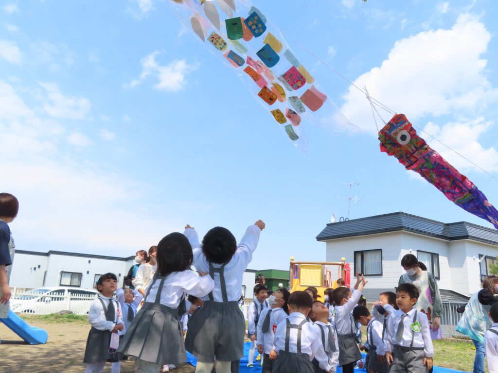 空にあがったこいのぼりを見て興奮する園児たち