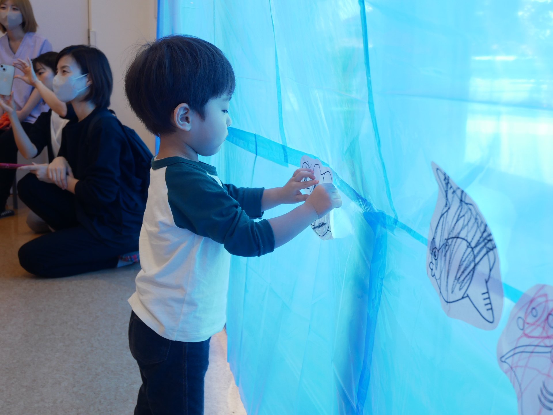自分で塗った魚の絵を飾る園児たち